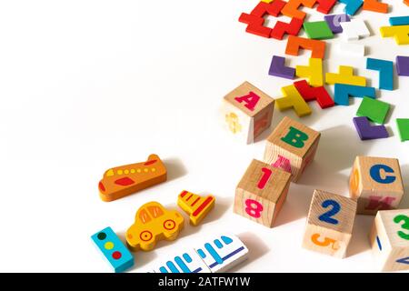 Giocattoli colorati per bambini su sfondo bianco. Frame dallo sviluppo di blocchi colorati, auto e aeroplano, puzzle. Vista dall'alto. Disposizione piatta. Copiare lo spazio per il testo Foto Stock