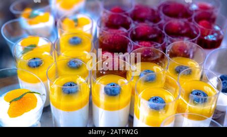 Bicchieri con budino bianco da dessert a strati sani, alcuni mango, mirtilli e lamponi Foto Stock