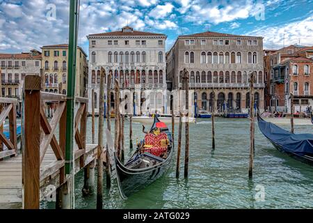 Una gondola vuota ormeggiata ad un palo di legno sul tratto di Rialto del Canal Grande, Venezia, Italia Foto Stock
