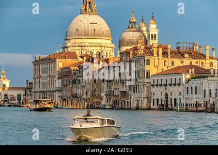 Un taxi acquatico fa strada lungo il Canal Grande di Venezia con l'imponente cupola della Basilica di Santa Maria della Salute sullo sfondo Foto Stock