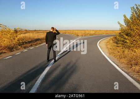 L’uomo d’affari confuso si trova a un bivio. Concetto di scelta Foto Stock