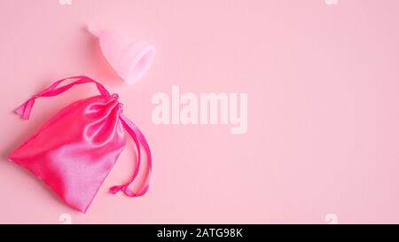 Coppa mestruale e custodia su sfondo rosa con spazio di copia. Alternativa eco-compatibile riutilizzabile a tamponi e assorbenti igienici. Giorni critici, mestruazioni Foto Stock