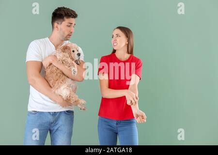 Giovane uomo con cane e sua moglie che soffre di allergia animale domestico su sfondo colore Foto Stock