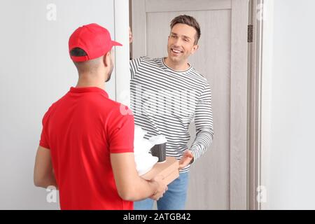 L'uomo che riceve l'ordine dal corriere dell'azienda di consegna del cibo Foto Stock