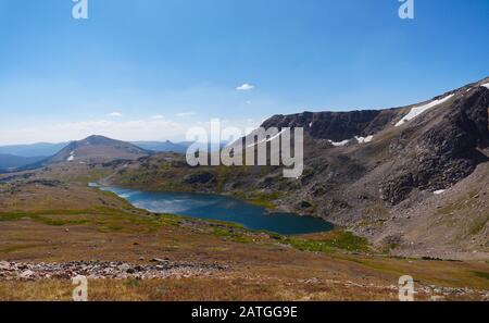 Guardando in basso su un lago scintillante ad alta quota e le montagne oltre dalla Beartooth Highway. Foto Stock