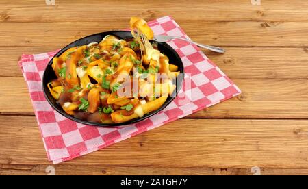 Ciotola di tradizionale poutine canadese su uno sfondo di legno Foto Stock