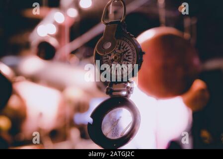 Bellissimo bokeh di fondo di una bussola appeso con luci e riflessioni in background. Concetto di essere perduti, libertà e ricerca della felicità. Foto Stock