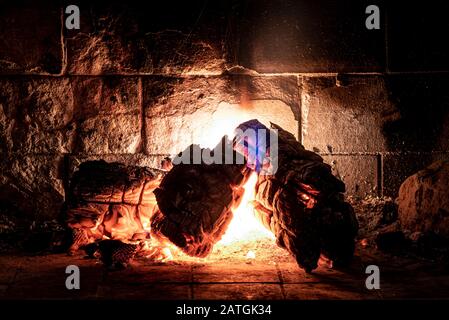 Trifoseup di legna da ardere che brucia in fuoco con esposizione lunga, fiamme come luce incandescente e ombre molli. Concetto di tranquillità, relax e silenzio. Foto Stock