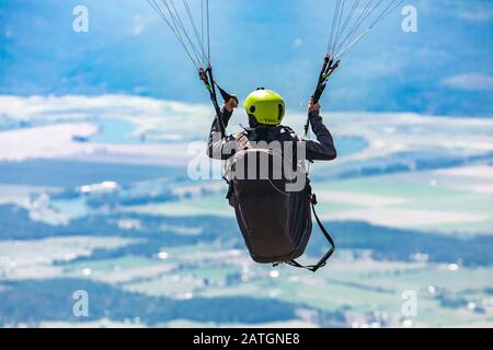 Parapendio volante. Vista da dietro. Kootenay valle montagne sullo sfondo. Amanti del parapendio divertirsi a Creston, British Columbia, Canada Foto Stock