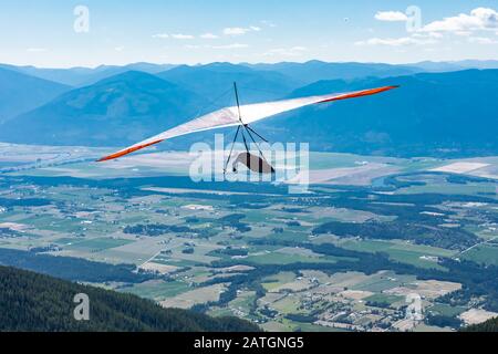 Il deltaplano si trova sopra la collina e la città. Deltaplano in azione. Delta deltaplano approfittare della bella giornata Foto Stock