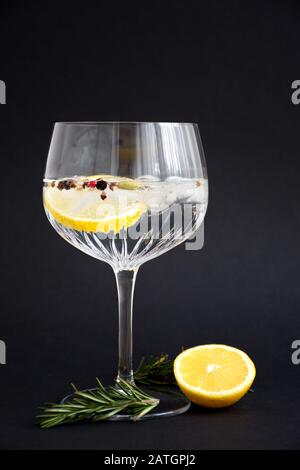 Gin e tonico con limone e rosmarino in cristallo sullo sfondo nero Foto Stock