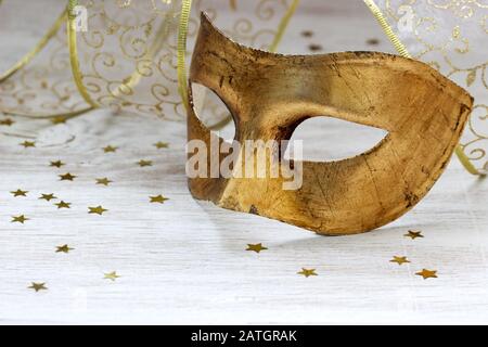 Maschera carnevale dorata, nastro e stelle d'oro su sfondo chiaro. Foto Stock