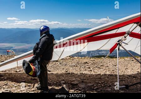 Pilota professionista in piedi vicino con i suoi deltaplani e sempre pronto a volare. Hobby estremo e rischioso. Parapendio sulla collina Foto Stock
