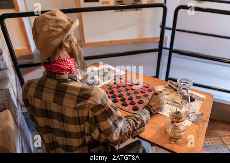 Cera figura di uomo contadino che gioca a dama. Attività di svago di persone rurali. Manichino contadino in abbigliamento casual giochi da tavolo Foto Stock