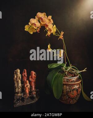 Ancora vita con orchidee fiorite e statuette onice. Vintage. Foto Stock