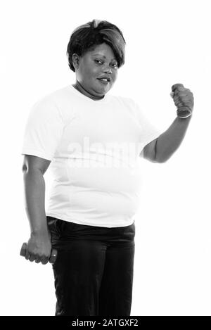 Studio scatto di felice grasso nero donna africana sorridente mentre alzando dumbbell pronto per la palestra Foto Stock