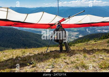 Giovane parapendio che si prepara a decollare da terra. Gli amanti degli sport estremi si divertano nel weekend a Creston, British Columbia, Canada Foto Stock