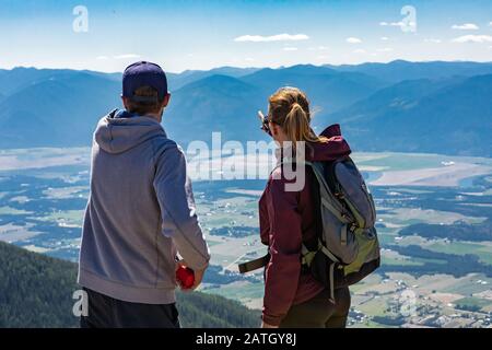 Giovani uomini e donne si levano in piedi sulla cima della collina e parlano della loro direzione di percorso. Montagne della valle di Kootenay, in Creston, Columbia Britannica, Canada Foto Stock