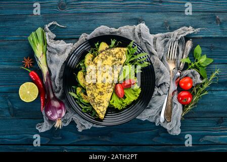 Omelette con verdure e avocado. Uova fritte. Su uno sfondo di legno. Vista dall'alto. Spazio libero di copia. Foto Stock