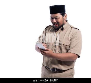 Lavoratore aziendale con marrone uniforme di indonesia sorridente mentre si utilizza il telefono cellulare isolato su sfondo bianco Foto Stock