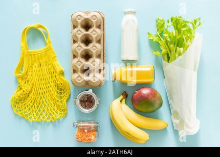 Concetto di shopping a zero sprechi - generi alimentari e sacchetti riutilizzabili su sfondo blu Foto Stock