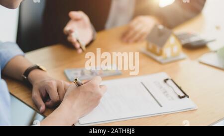 Vista ravvicinata dell'agente immobiliare che dà la chiave della casa al suo cliente durante la firma del contratto di prestito domestico Foto Stock