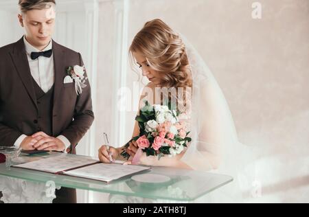 sposa e sposo firma il contratto di matrimonio. Foto Stock