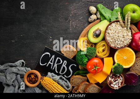 Alimenti con carboidrati naturali: Pane, pasta, avocado, farina, zucca, broccoli, fagioli, spinaci. Su sfondo marrone. Vista dall'alto. Spazio libero di copia. Foto Stock