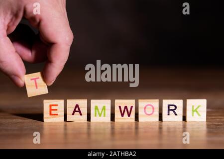 Mano mettere blocchi di legno con lettere in una riga, parola Teamwork Foto Stock
