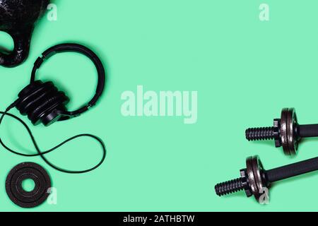 Foto sportive. Kettlebells e manubri di menta su sfondo verde. Appartamento laico, vista dall'alto, copia dello spazio. Foto Stock