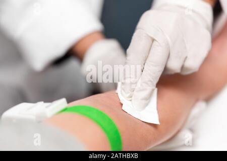 Preparazione per il prelievo di sangue, paziente con una banda di laccio emostatico e tampone sul braccio, a closeup Foto Stock