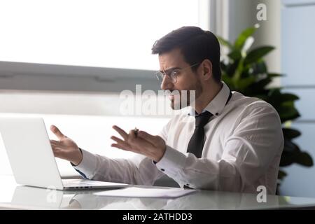 L'uomo d'affari indignato guarda lo schermo del pc che ha problemi con il laptop Foto Stock