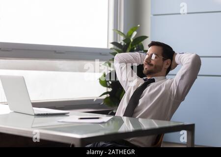 L'uomo d'affari ha messo le mani dietro la testa godere la giornata fuori sul posto di lavoro Foto Stock