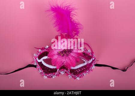 Elegante maschera veneziana di colore fucsia su sfondo rosa. Prendere dall'alto. Concetto di festa Foto Stock