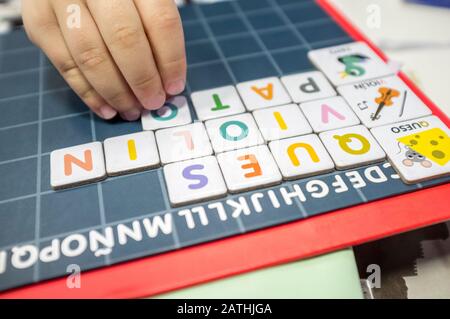 Pratiche del bambino con il gioco del bordo di formazione di parola. Il gioco è fatto con pezzi di lettera magnetica. Messa a fuoco selettiva Foto Stock