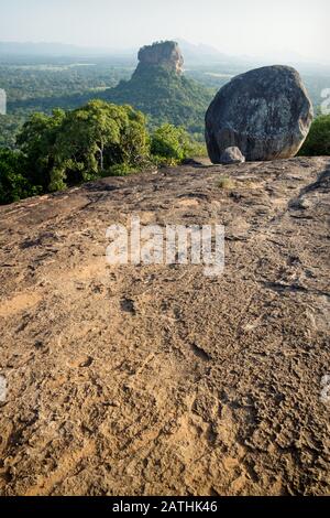 Big Stone sul soleggiato arancione Pidurangala Rock con vista sul Lions Rock verticale a Sigiriya, Sri Lanka Foto Stock