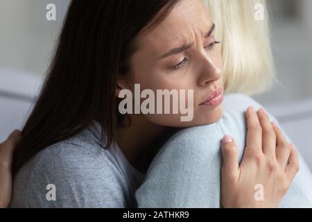 Mamma e figlia adulta sconvolti abbracciano mostrando supporto e cura Foto Stock
