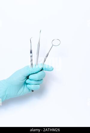 Primo piano di medico dentista femmina mano che tiene gli attrezzi dentari. Gli strumenti in studio dentistico. Isolato su sfondo bianco Foto Stock