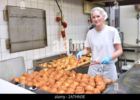 Lavoratore femminile in una grande panetteria - produzione industriale di prodotti da forno su una linea di assemblaggio Foto Stock