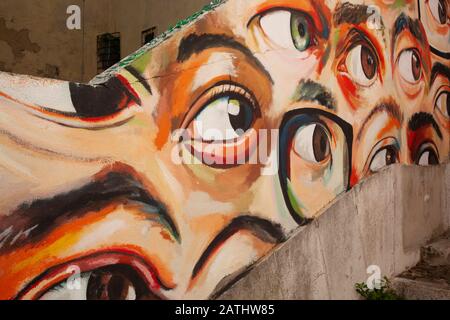 Esempio di arte di strada, o graffiti, che adorna le mura di Lisbona, Portogallo. Questo è occhi multipli su un muro in un vicolo. Foto Stock