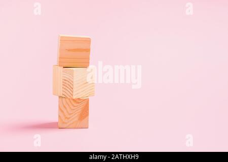 Torre di cubetti di legno su sfondo rosa. Giocattoli per bambini dal concetto di materiali naturali zero West. Spazio copia cornice orizzontale Foto Stock