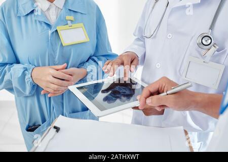 Gruppo di medici che controllano i raggi X del cranio su un computer tablet e che progettano la chirurgia Foto Stock