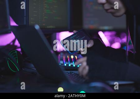 Primo piano di irriconoscibile cyber sicurezza hacker indossare cappa mentre si lavora sulla programmazione in camera oscura, copia spazio Foto Stock