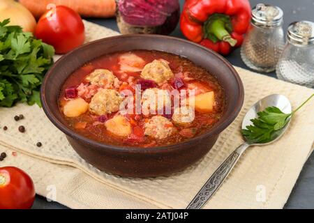 Zuppa con polpette e verdure in una ciotola scura Foto Stock