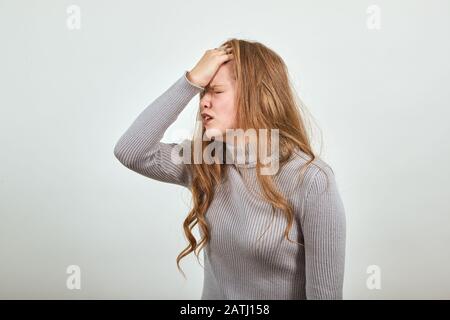 la donna dai capelli rossi nel maglione grigio mostra l'emozione dei problemi di dolore Foto Stock