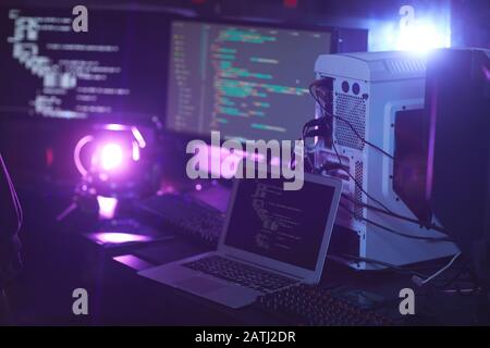 Immagine di sfondo di varie apparecchiature informatiche con codice di programmazione su schermi in stanza oscura, concetto di cyber sicurezza, spazio di copia Foto Stock