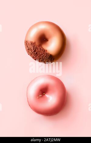 Ciambelle con glassa e cioccolato su sfondo rosa pastello. Ciambelle dolci. Foto Stock