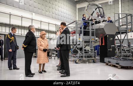 La regina Elisabetta II, con il comandante della stazione James Beck (a sinistra), viene salutata dal personale durante una visita alla Royal Air Force Marham, Norfolk. Foto Stock