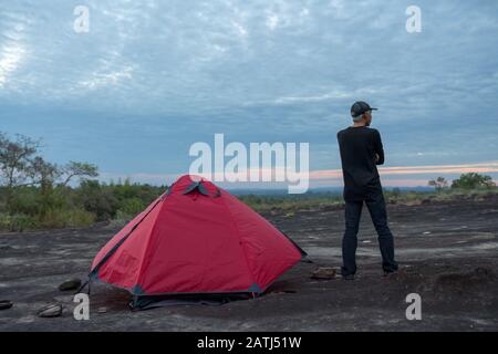 Backpacker in piedi accanto alla tenda libertà sensazione sulla collina durante il tramonto Foto Stock