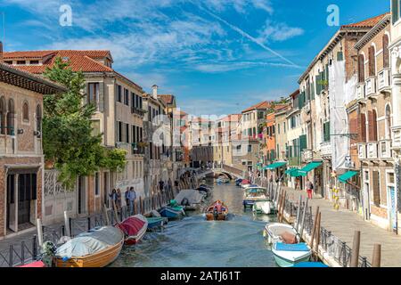 Persone che camminano oltre le barche ormeggiate lungo il Rio de la Cazziola e de ca rizzi nel quartiere Dorsoduro di Venezia Foto Stock